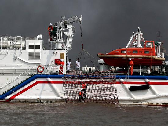 Drowning sailors are saved by a rescue ship during the oil slick emergency response drill. （Photo by Shen Lei/For China Daily）