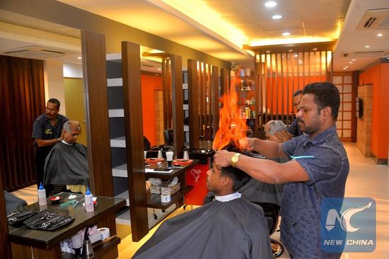 A barber uses fire to cut hair at a hair salon in Dhaka, Bangladesh on Aug. 29, 2018. (Xinhua/Naim-ul-karim)