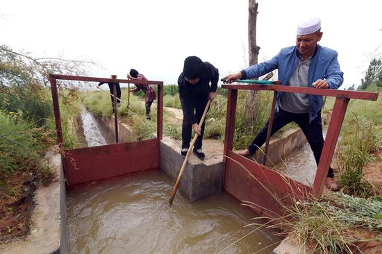 A woman from the Hui ethnic group helps clear an irrigation channel in Hualong Hui autonomous county, Qinghai province. （Photo By Deng Jia / Asian Development Bank）