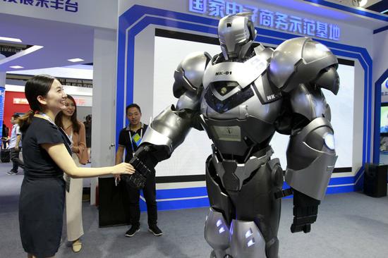 A visitor to a service trade expo interacts with a robot on display at the event. (Photo by A Jing/For China Daily)