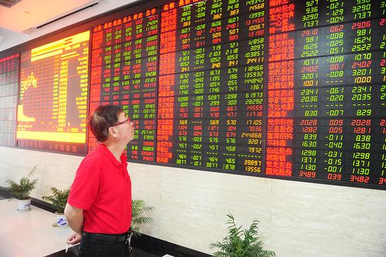 An investor looks at share prices at a brokerage in Fuyang, East China's Anhui Province. (Photo by Wang Biao/For China Daily)