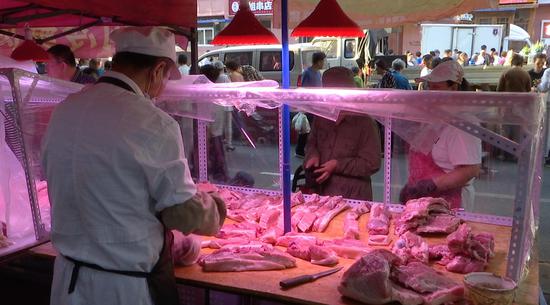 A pork vendor in Shenyang, Liaoning Province sees his prices rising due to natural disasters and more expensive soybean pulp-based pig feed. /CGTN Photo
