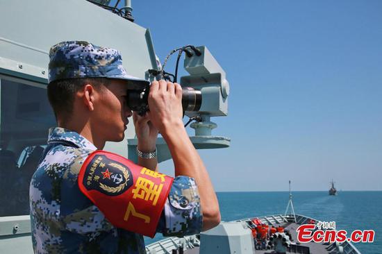 A Chinese soldier watches through a telescope onboard Chinese frigate Huangshan during Exercise KAKADU 2018 at sea off the coast of Darwin, Australia, Sept. 6, 2018. (Photo: China News Service/Xu Guang)