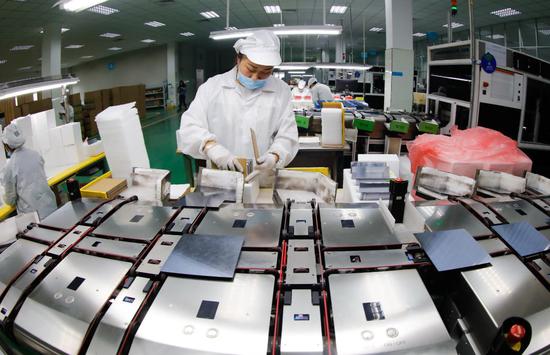 An employee of a Jiujiang, Jiangxi province-based photovoltaic products producer puts finishing touches to PV products at an assembly line in Jiujiang. (Photo by Zhang Haiyan/ For China Daily)