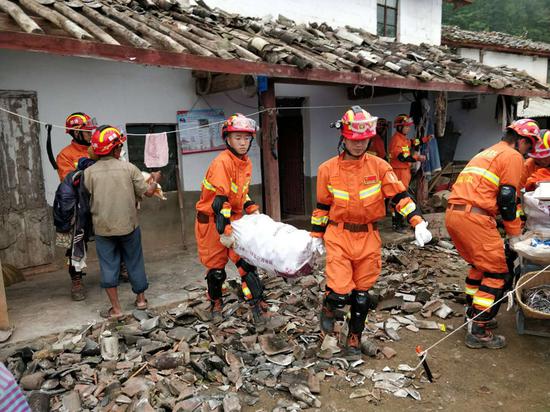 Rescuers help villagers move their belongings in a village in Mojiang Hani autonomous county, Yunnan province, on Sunday. A magnitude 5.9 earthquake hit the region on Saturday morning. (Provided to China Daily)