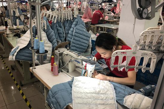 Employees work at Jintongwang Dress Co in Zhili, Zhejiang province. The company produces one of China's top brands of children's clothing. (Photo by Ma Zhenhuan/China Daily)