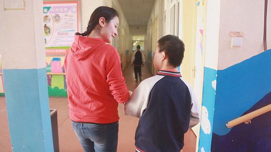 Teacher Xue Siluo helps a student to walk after class. (Photo/CGTN)