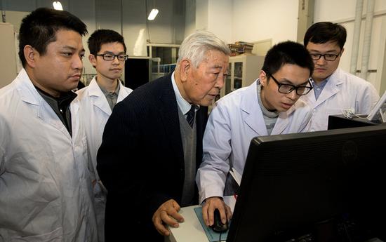 Academician Zhao Zhongxian discusses superconductive materials with his students in Beijing. (Photo/Xinhua)
