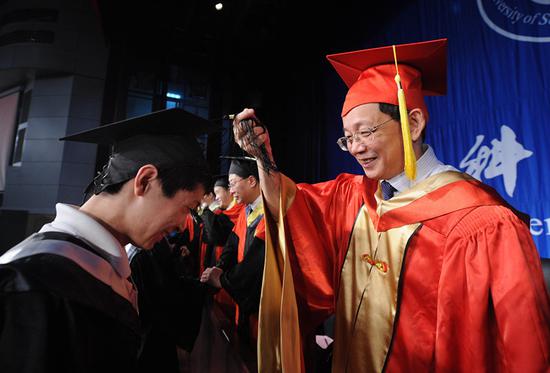 Hou Jianguo, vice president of the Chinese Academy of Sciences, interacts with a graduate at a ceremony in Anhui Province. (Photo/Xinhua)