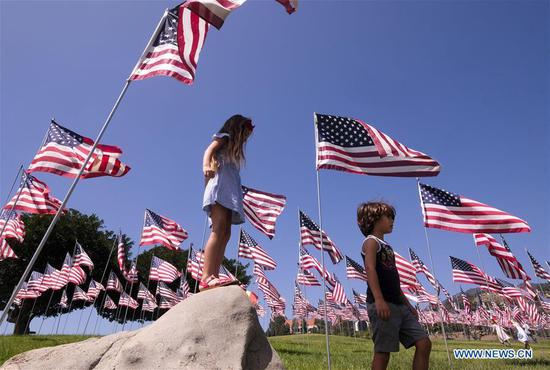 Children play among U.S. national flags erected to honor the victims of the September 11, 2001 attacks in New York, at the campus of Pepperdine University in Malibu, the United States, Sept. 10, 2018. (Photo/Xinhua)