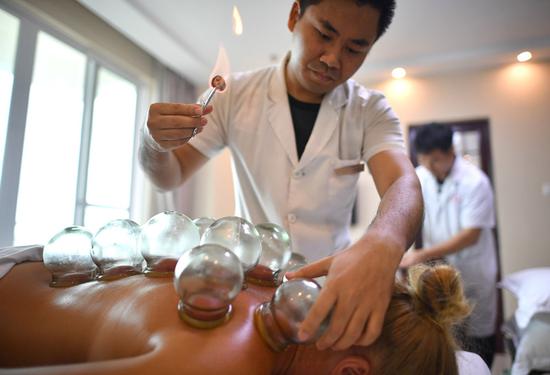 Russian tourists receive traditional Chinese medicine therapy from medical staff at Sanya International Friendly Chinese Medicine Sanatorium in Hainan Province in June. (GUO CHENG / XINHUA)