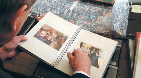 Stephen Perry, chairman of the 48 Group Club, leafs through a photo album showing some of the activities he has taken part in when in China. (Photo by Kevin Wang/China Daily)