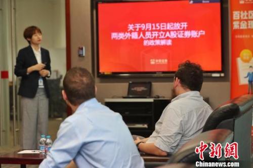 Two foreigners ask a securities broker about opening an A-shares account.  (Photo/China News Service)