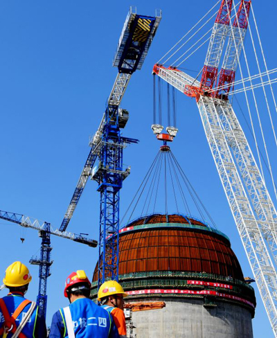 Workers install the dome atop the reactor of Fuqing nuclear power plant of China National Nuclear Corp on March 21. （Photo/Xinhua）