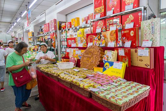 A consumer shops for mooncakes packaged in attractive gift boxes in the run-up to Mid-Autumn Festival at a Daoxiangcun store in Beijing in August. (Photo by Zhao Rong/for China Daily)
