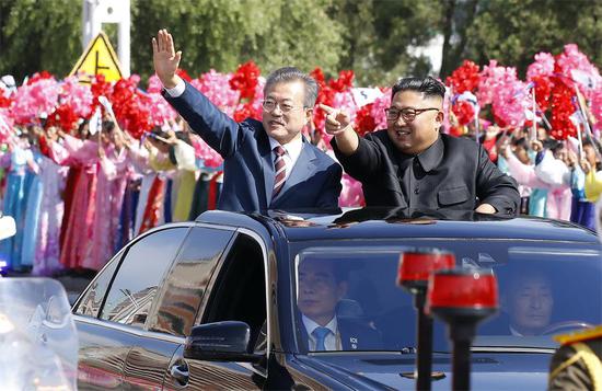 During a motorcade procession, Republic of Korea President Moon Jae-in and Democratic People’s Republic of Korea top leader Kim Jong-un greet a welcoming crowd in Pyongyang on Tuesday. (Photo/Xinhua)