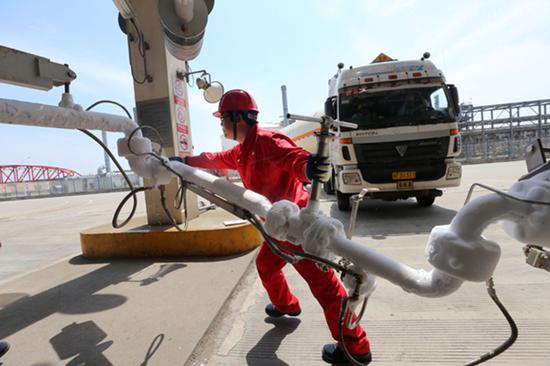 An employee shifts the LNG pipeline after filling the transport vehicle at the CNPC LNG center in Jiangsu Province. (Photo by Xu Congjun/for China Daily)