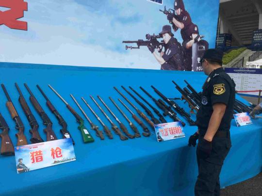 A policeman looks at guns seized in recent years at a ceremony in Guangzhou, South China's Guangdong province, on Sept 20, 2018. （Photo by Zheng Caixiong / chinadaily.com.cn）