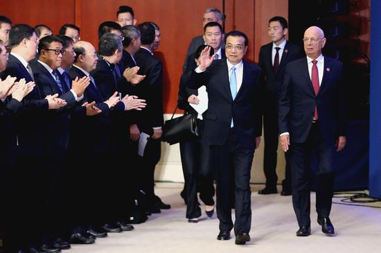 Premier Li Keqiang and Klaus Schwab, founder and executive chairman of the World Economic Forum, greet participants of the Annual Meeting of the New Champions 2018 in Tianjin, while entering the forum’s opening ceremony on Wednesday. (Photo by Wu Zhiyi/China Daily)