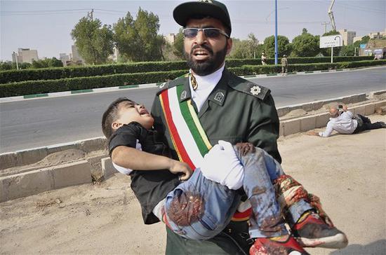 An Iranian soldier carries an injured boy during a terror attack in a military parade in Ahvaz, Iran, Sept. 22, 2018. At least 24 people were killed in a terror attack in a military parade in southwestern Iranian Ahvaz city on Saturday, official IRNA news agency reported. (Photo/Xinhua)