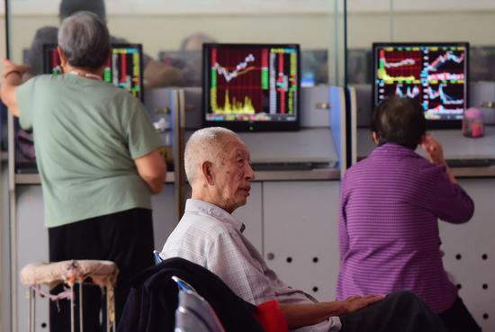 Investors monitor stock prices at a brokerage in Fuyang, Anhui Province. (Photo by Lu Qijian/for China Daily)