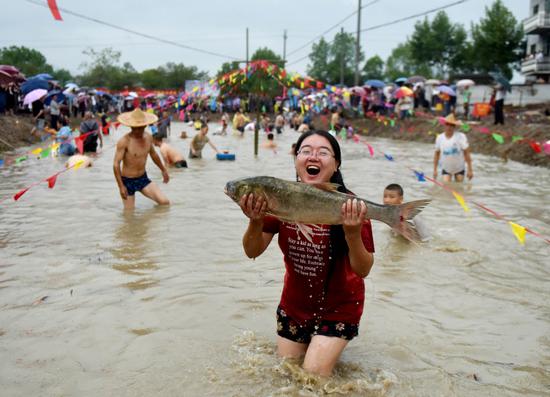 A woman is a winner on Sunday in a paddy where people caught fish barehanded in Wuyi county, Zhejiang province, for the Chinese Farmers' Harvest Festival. (ZHANG JIANCHENG/FOR CHINA DAILY)