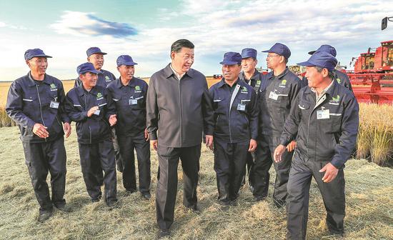 President Xi Jinping talks with workers at a State-owned farm in Jiansanjiang, Heilongjiang province, on Tuesday, the first day of his inspection visit to the province. He had detailed talks with farmworkers and managers on production and management. (Photo/Xinhua)