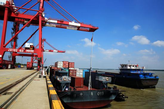 Workers load containers on to a cargo ship at a dock at Jiujiang Port, which is run by Shanghai International Port (Group) Co Ltd, along the Yangtze River in central China's Jiangxi Province on June 9, 2013. (Photo by Zhang Haiyan / Asianewsphoto)