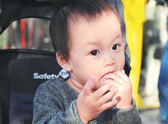 Zhang Junyao, a one-year-old girl, enjoys biscuits on her baby cart. (Photo by Wang Jingjing / for China Daily)