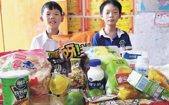 Yuan Jinghao and Zhu Xinyu, two cousins born in 2008 and 2009, proudly pose together with their snacks. However, the daily amount of snacks they are allowed to take is limited. (Provided to China Daily)