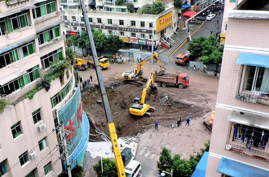 Excavators clear the site to facilitate the search for trapped people after a sidewalk collapsed in Dazhou, Sichuan province, on Sunday. (Photo/CHINA DAILY)