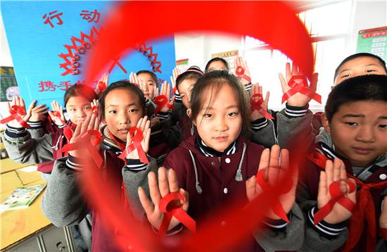Elementary school students in Donghai county in Jiangsu Province crafted red ribbons as part of an HIV/AIDS prevention campaign. (File photo by ZHANG ZHENGYOU/FOR CHINA DAILY)