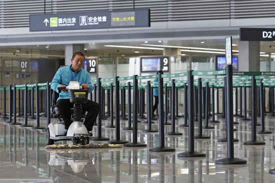 A staff member cleans the floor and makes final checks at Terminal 1 of the Hongqiao International Airport in Shanghai on Tuesday, before it reopens after a three-year renovation. (YIN LIQIN/CHINA NEWS SERVICE)