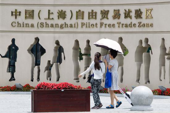 Pedestrians walk past the entrance of the China (Shanghai) Pilot Free Trade Zone. （Photo by Wu Jun/For China Daily）