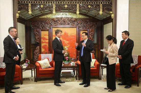 Premier Li Keqiang continues his conversation with Harald Kruger, BMW's chairman of the board of management, at the Zhongnanhai leadership compound in Beijing on Wednesday, after their formal meeting that focused on foreign investment. (Photo by Feng Yongbin/China Daily)