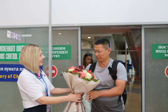 The first Chinese traveler to arrive at Minsk National Airport in Belarus under the new visa-free agreement receives flowers from an airport employee. China and Belarus implemented visa-free policies for their respective citizens on Aug. 10. (Photo/Xinhua)