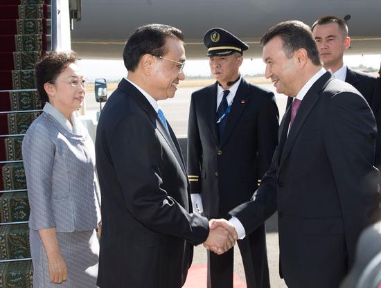 Premier Li Keqiang and wife, Cheng Hong, are greeted by Tajik Prime Minister Kokhir Rasulzoda on Thursday in Dushanbe for an official visit to Tajikistan. Li will also attend the 17th meeting of the Shanghai Cooperation Organization Heads of Government Council. (Photo/Xinhua)