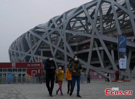 Tourists visit the area around National Stadium, also known as the Bird's Nest, on a smoggy day in Beijing, Oct. 14, 2018. (Photo: China News Service/Liu Guanguan)