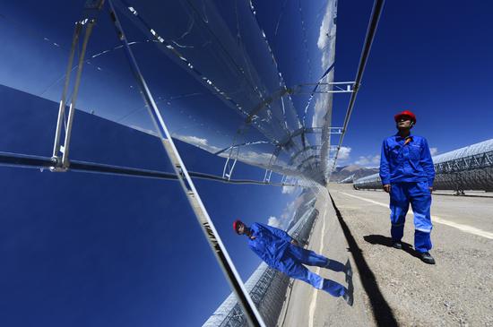 An employee of CGN New Energy Holdings inspects solar panels at a power plant in Golmud, Qinghai Province. (Photo/Xinhua)