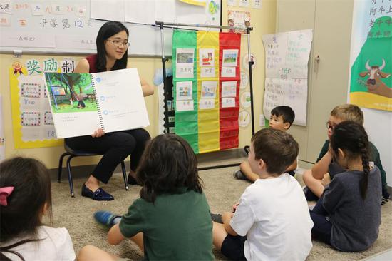 Yang Ying, a Chinese teacher at HudsonWay Immersion School in New York, is teaching kindergarten students how to make plasticine in classroom in Chinese. (ZHANG RUINAN/CHINA DAILY)
