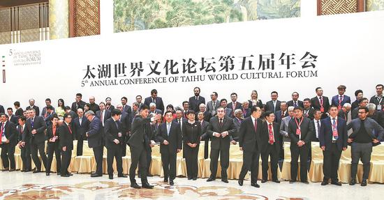 Taihu World Cultural Forum attendees head for the annual conference’s opening ceremony in Beijing on Thursday after taking a group photo. (Photo/CHINA DAILY)
