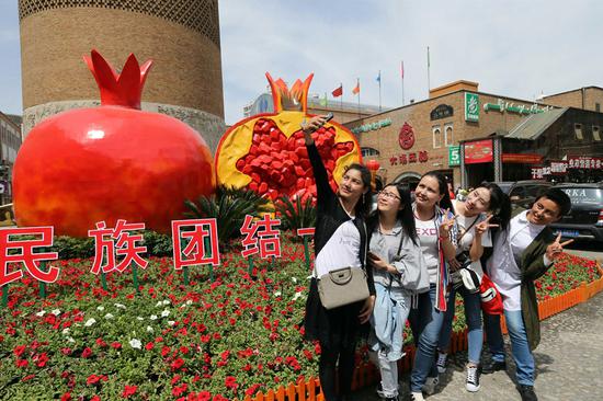 Visitors pose for a selfie at the entrance of the Xinjiang International Bazaar in Urumqi, capital of the Xinjiang Uygur autonomous region. (Photo by Li Xiongxin/For China Daily)