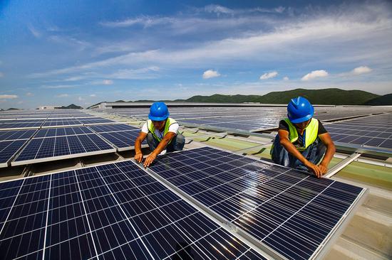 Workers install solar power generation panels in Dinghai district of Zhoushan, Zhejiang Province, on July 9.  (Photo by Yao Feng/For China Daily)
