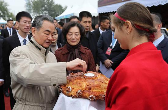 State Councilor and Foreign Minister Wang Yi (left) samples Russian food at an international charity fair in Beijing on Sunday with his wife, Qian Wei, chief coordinator of the event this year. (WANG ZHUANGFEI/CHINA DAILY)