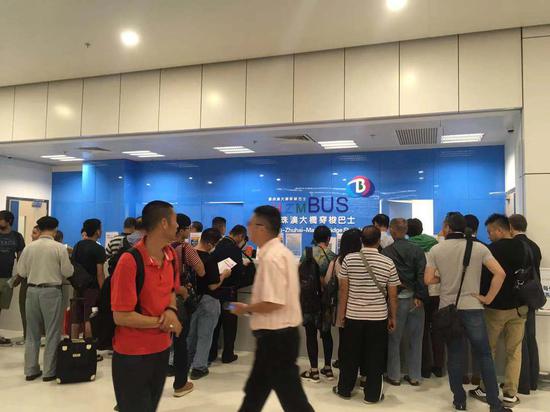 Passengers purchase shuttle bus tickets at Macao Port as the Hong Kong-Zhuhai-Macao Bridge opens to traffic Wednesday morning. (Li Bingcun / China Daily)