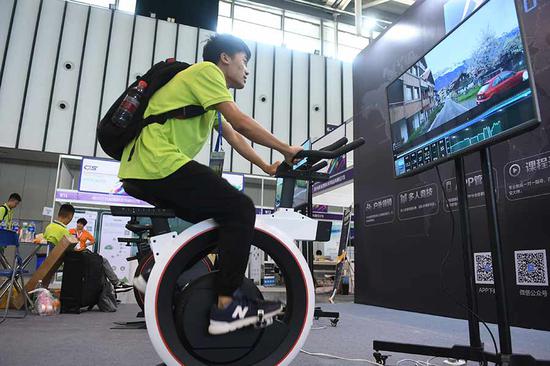 A visitor tries out a bicycle-riding video game on a simulator at a software exhibition in Nanjing, capital of Jiangsu Province.  (Photo by Cui Xiao/for China Daily)