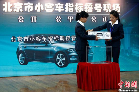 Two staff members announce results of vehicle plate lottery in Beijing. (File photo/China News Service)