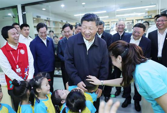 President Xi Jinping, also general secretary of the Communist Party of China Central Committee, greets children at a community center in Shenzhen, Guangdong province, during an inspection tour on Wednesday. (JU PENG / XINHUA)