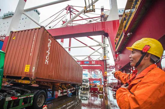 An employee oversees loading of containers at Qingdao Port, Shandong Province. (Photo by Zhang Jingang/for China Daily)
