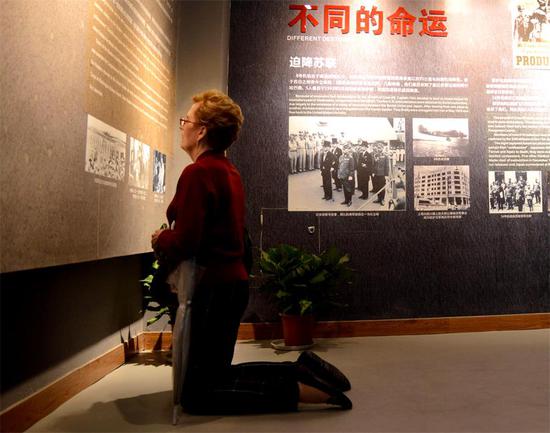 Susann Ozuk from the United States kneels before a photo of the Doolittle Raid, the first US reprisal attack on Japanese soil during World War II, at the Memorial Hall to the Doolittle Raid in Quzhou, Zhejiang province, on Thursday. After bombing Tokyo, the US crews, including her father, crash landed in China and were rescued by locals.  (Photo/China Daily)
